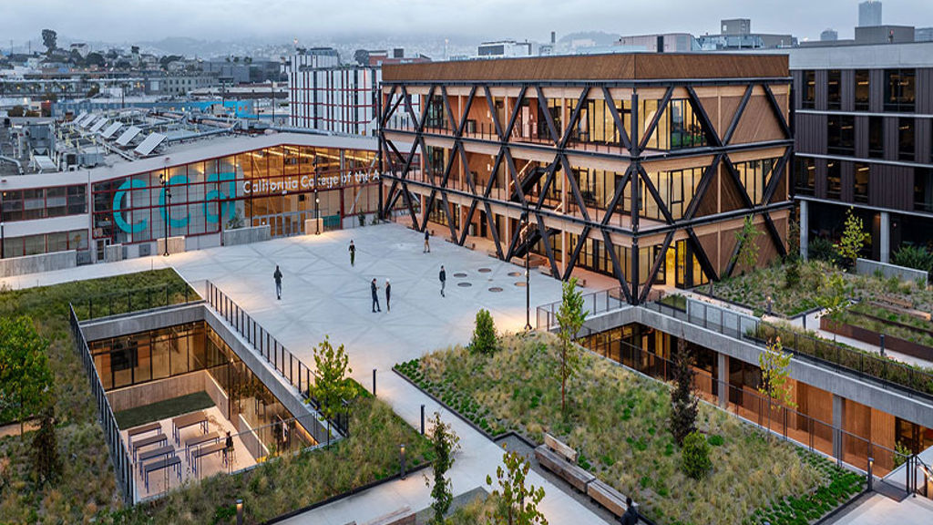 A large building with a courtyard and people walking around.